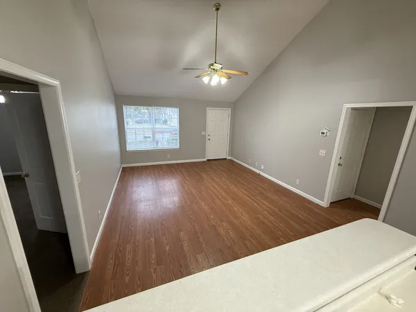 a view of an empty room with wooden floor and a window