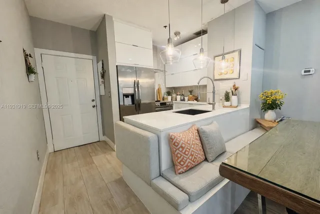 a kitchen with stainless steel appliances a refrigerator a sink dishwasher a oven with white cabinets and wooden floor