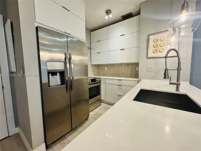 a kitchen with granite countertop stainless steel appliances a sink and a refrigerator