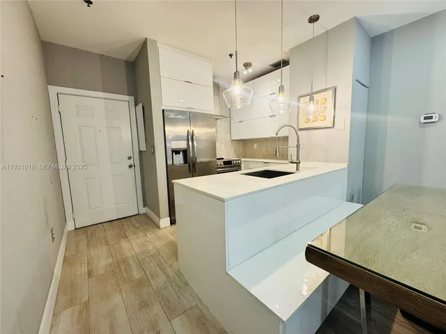 a kitchen with kitchen island white cabinets and refrigerator