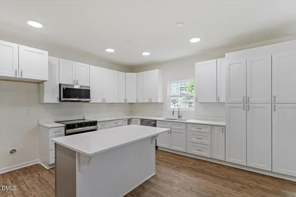 a kitchen with cabinets stainless steel appliances and wooden floor