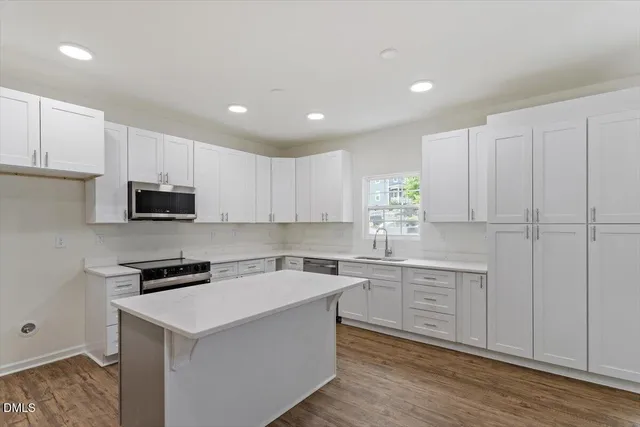 a kitchen with cabinets stainless steel appliances and wooden floor