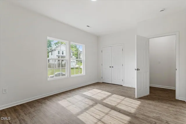 a view of an empty room with wooden floor and a window