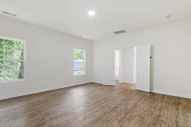 an empty room with wooden floor and windows