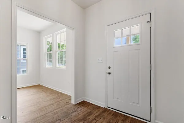 an empty room with wooden floor closet and windows