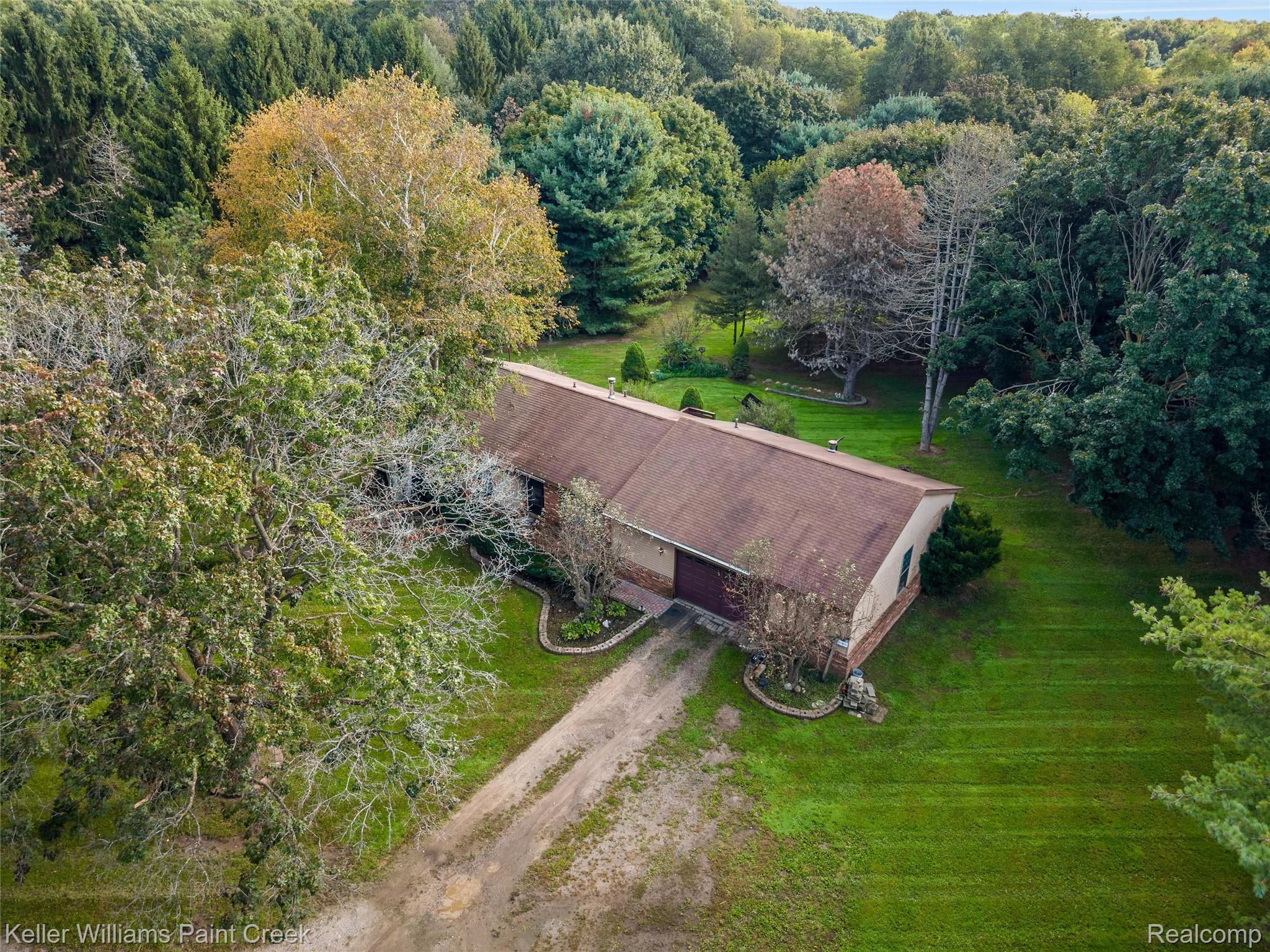 5077 Pinckney Road Howell, MI 48843 - Photo 25 of 39 Expansive property featuring a brown shingle roof, mature perimeter trees, a lush green lawn, and a natural terrain driveway