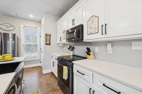 a kitchen with a sink a stove and white cabinets with wooden floor