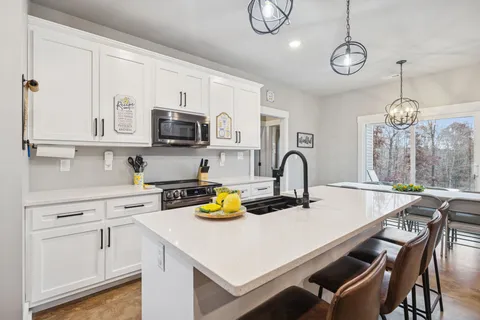 a kitchen with stainless steel appliances granite countertop a stove and a view of living room