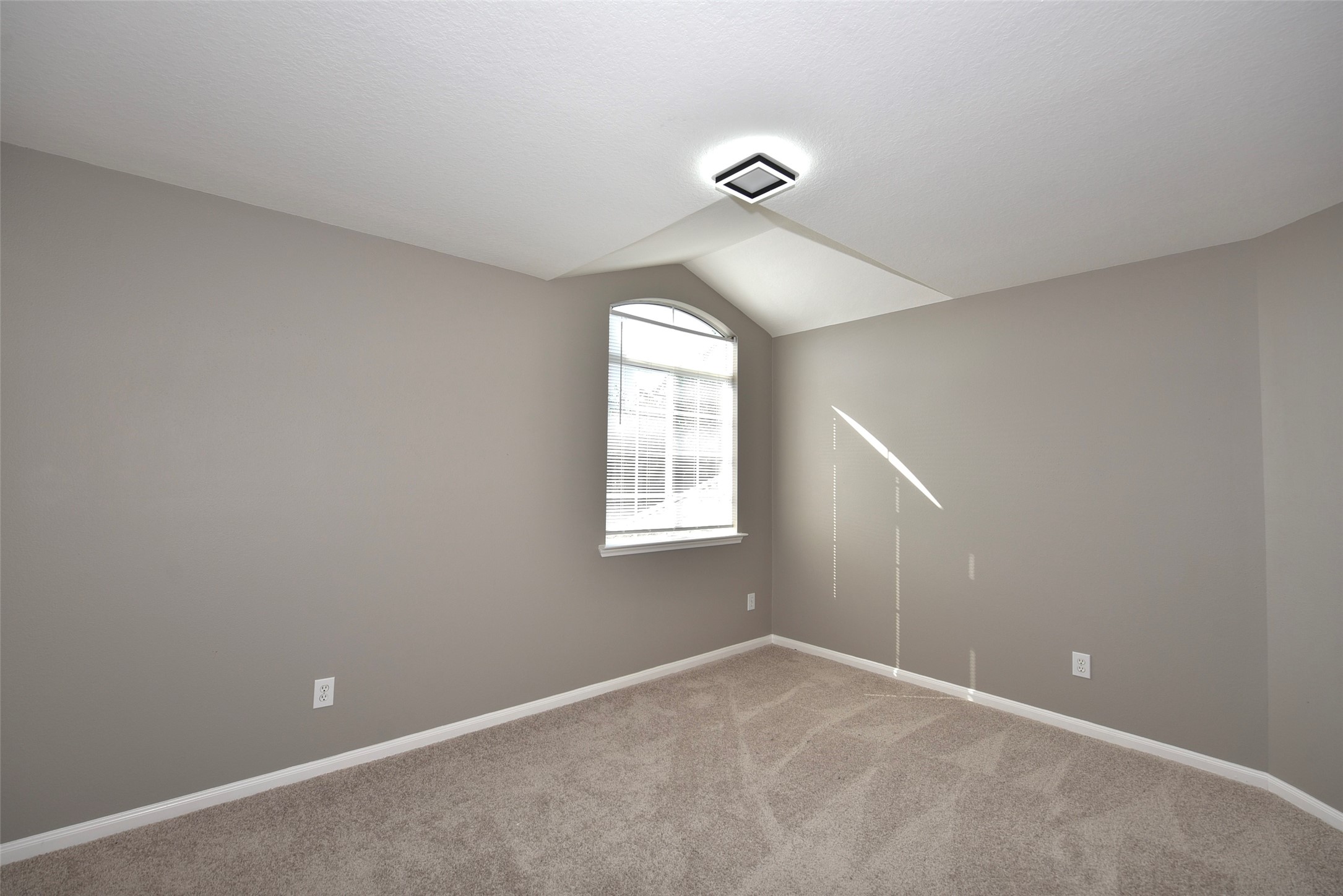 9611 Babbling Spring Court Tomball, TX 77375 - Photo 22 of 31 This is a cozy room with neutral walls and plush carpeting, featuring an arched window that lets in natural light. Ideal for a bedroom or office space.