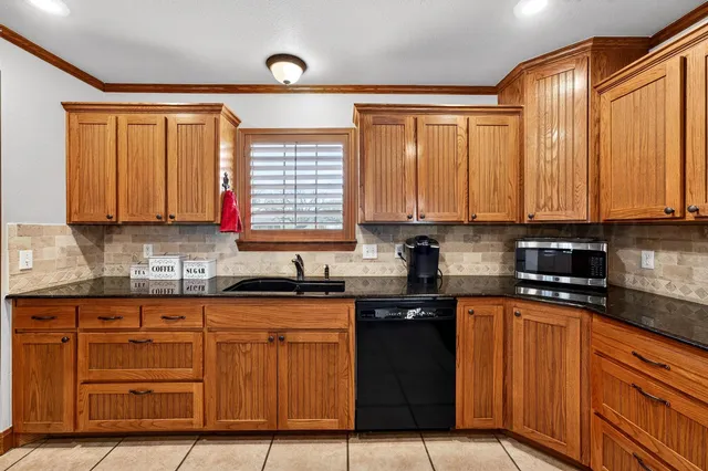 a kitchen with stainless steel appliances granite countertop a stove a sink dishwasher and a microwave oven with cabinets