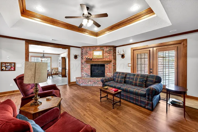 a living room with furniture a ceiling fan a fireplace and a large window