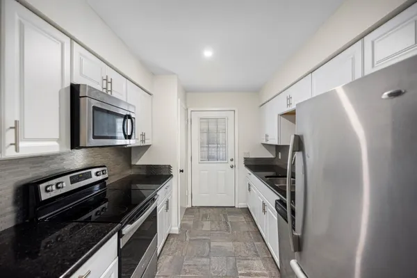 a kitchen with granite countertop a refrigerator and a stove