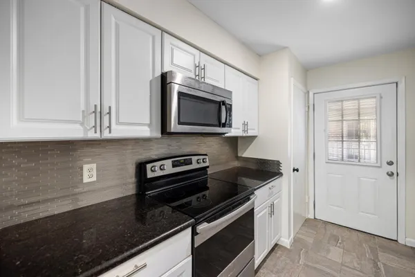 a kitchen with granite countertop white cabinets and black appliances