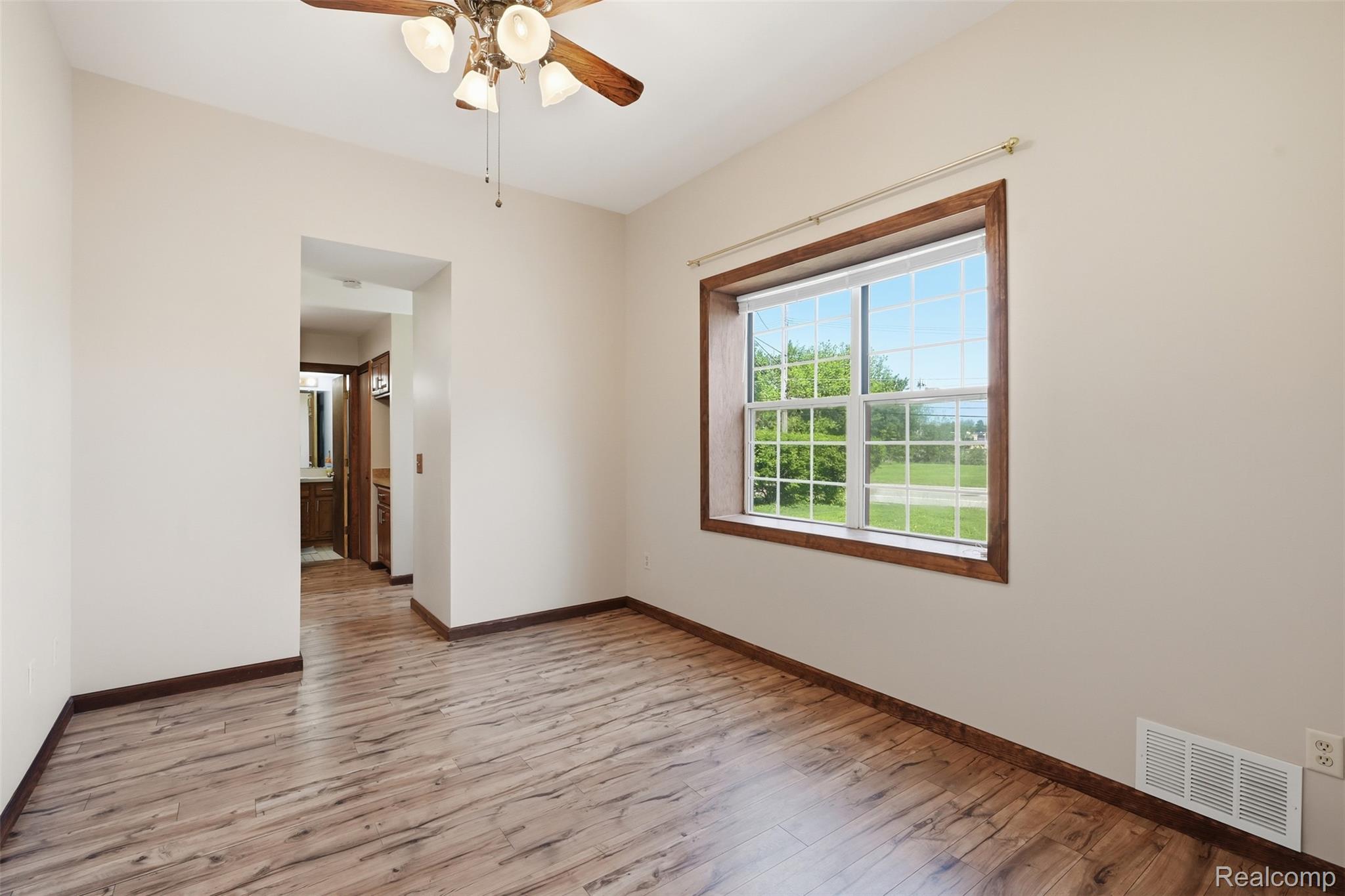 5634 Chicago Road Warren, MI 48092 - Photo 7 of 36 Room featuring wood-finish flooring, a ceiling fan with light fixture, and a large window with wood trim