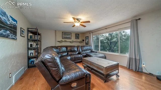 a living room with furniture a ceiling fan and a large window