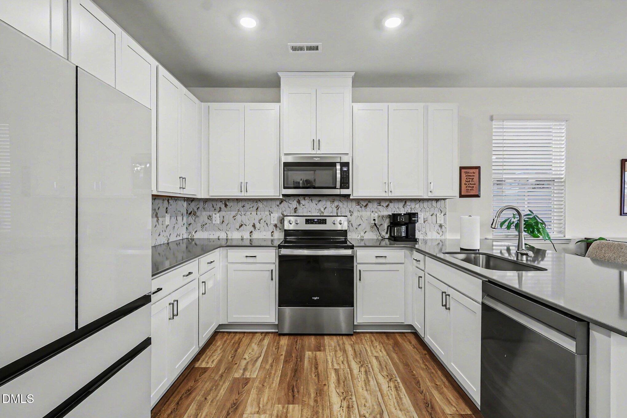 2732 Princess Tree Drive Raleigh, NC 27616 - Photo 6 of 32 a kitchen with a sink stove and white cabinets