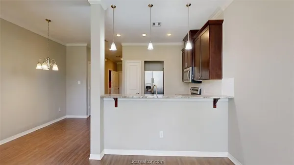 a view of a kitchen with kitchen island a sink wooden floor and a refrigerator