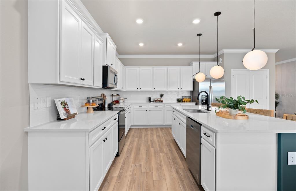 15918 Calm Key Loop Clermont, FL 34714 - Photo 11 of 57 a kitchen with kitchen island granite countertop a sink a stove cabinets and a dining table