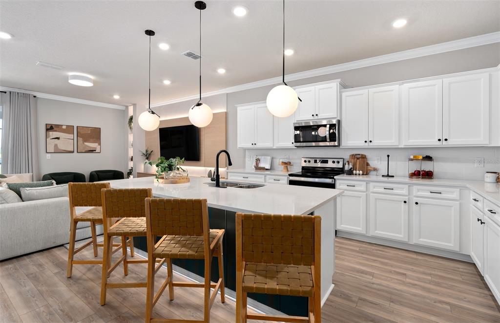 15918 Calm Key Loop Clermont, FL 34714 - Photo 9 of 57 a kitchen with stainless steel appliances kitchen island granite countertop a stove a sink a dining table and chairs with wooden floor