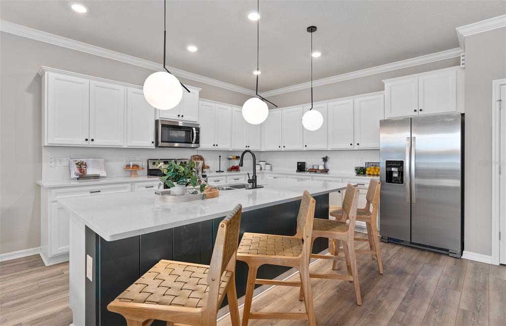 15918 Calm Key Loop Clermont, FL 34714 - Photo 10 of 57 a kitchen with stainless steel appliances a refrigerator a stove a sink dishwasher a microwave oven and a dining table with wooden floor