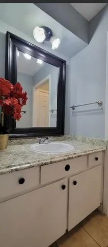 a bathroom with a granite countertop shower a mirror and a sink