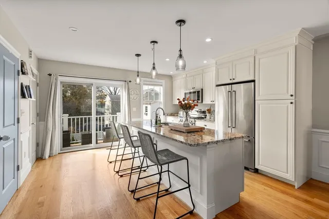 a kitchen with stainless steel appliances a dining table chairs refrigerator and cabinets