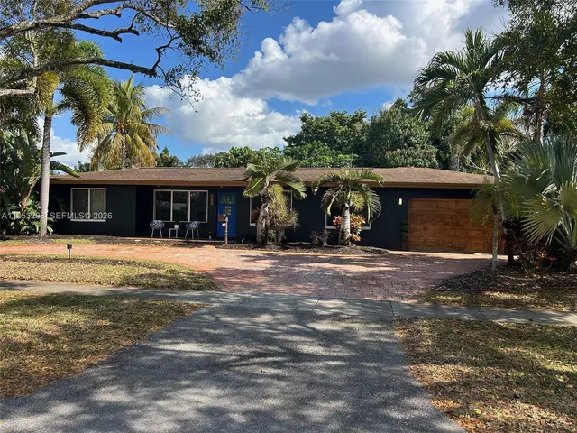 a view of a house with a yard and palm trees