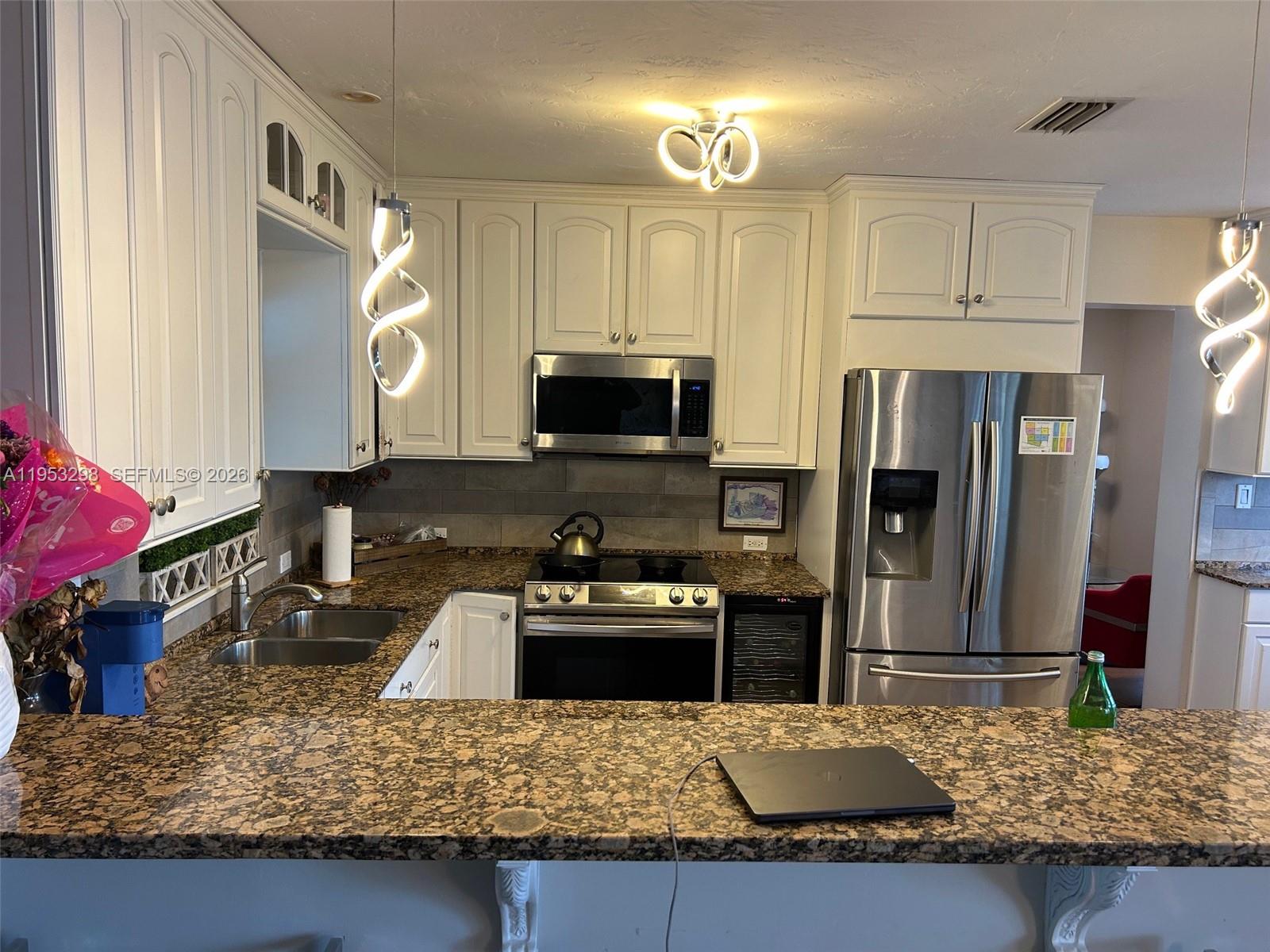 262 Southwest 54th Avenue Plantation, FL 33317 - Photo 14 of 16 a kitchen with stainless steel appliances granite countertop a sink refrigerator and microwave
