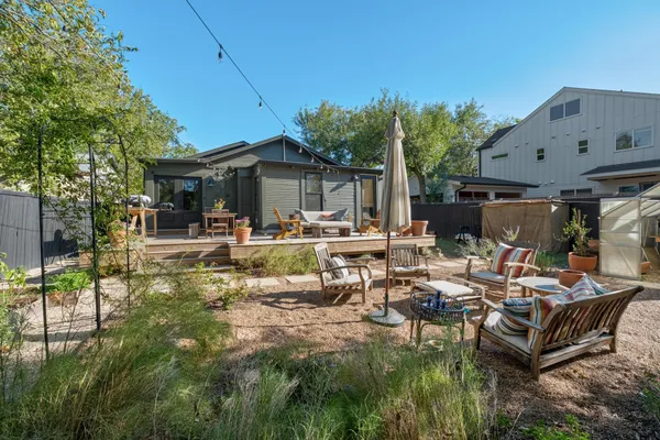 a view of a patio with table and chairs potted plants and large tree