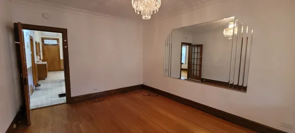 a view of an empty room with wooden floor and a mirror
