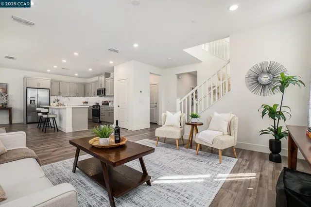 a living room with furniture potted plant and kitchen view