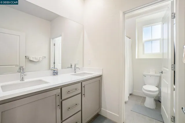 a bathroom with a granite countertop toilet sink and mirror