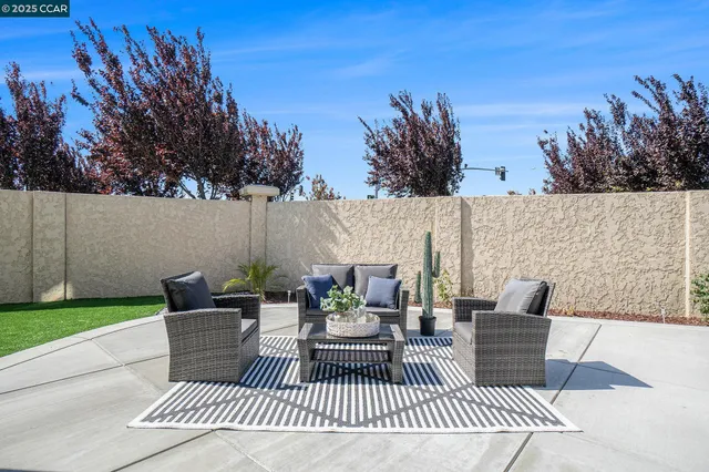 a view of a patio with couches and a table and chairs with wooden floor and fence