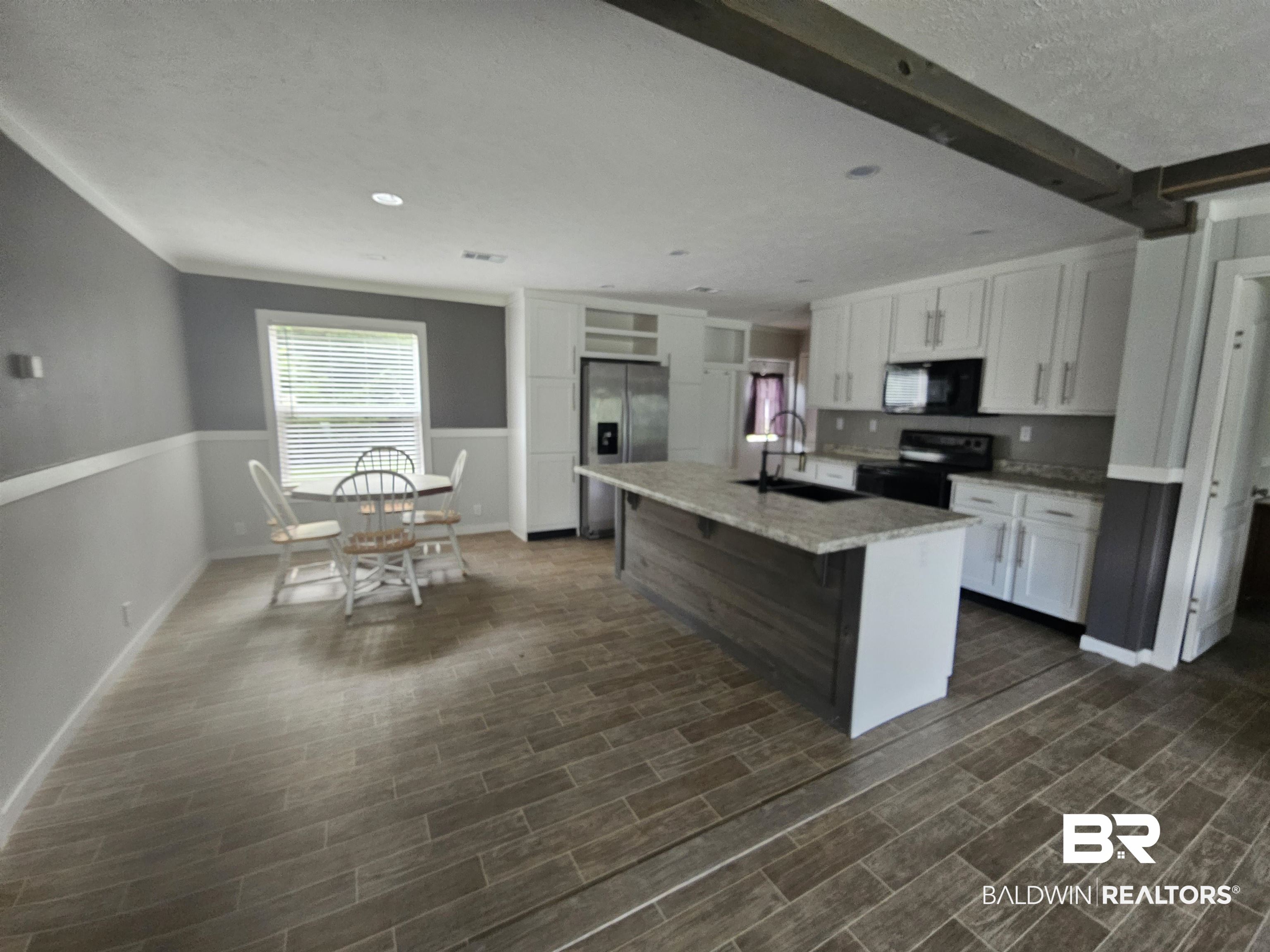 1863 Wait Road Monroeville, AL 36460 - Photo 5 of 38 Kitchen featuring black appliances, dark hardwood / wood-style flooring, white cabinets, an island with sink, and sink