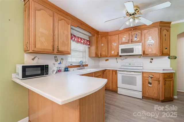 a kitchen with stainless steel appliances granite countertop a stove a sink dishwasher and a microwave oven with white cabinets