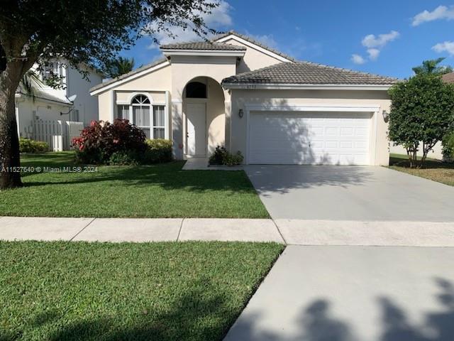 6553 Spring Meadow Drive Greenacres, FL 33413 - Photo 2 of 10 a front view of a house with a yard and garage