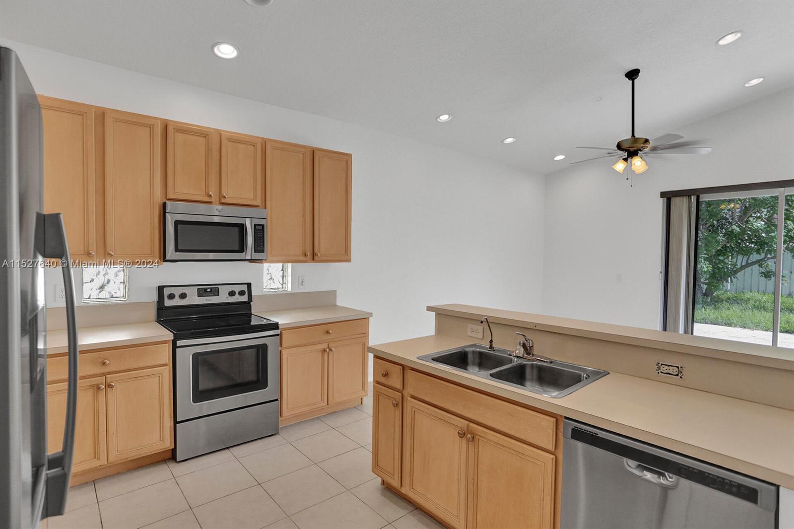 6553 Spring Meadow Drive Greenacres, FL 33413 - Photo 7 of 10 a kitchen that has a sink cabinets and stainless steel appliances