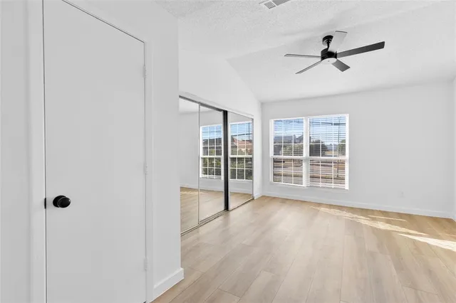 a view of empty room with wooden floor and fan