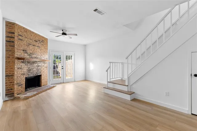 a view of an empty room with wooden floor fireplace and a window
