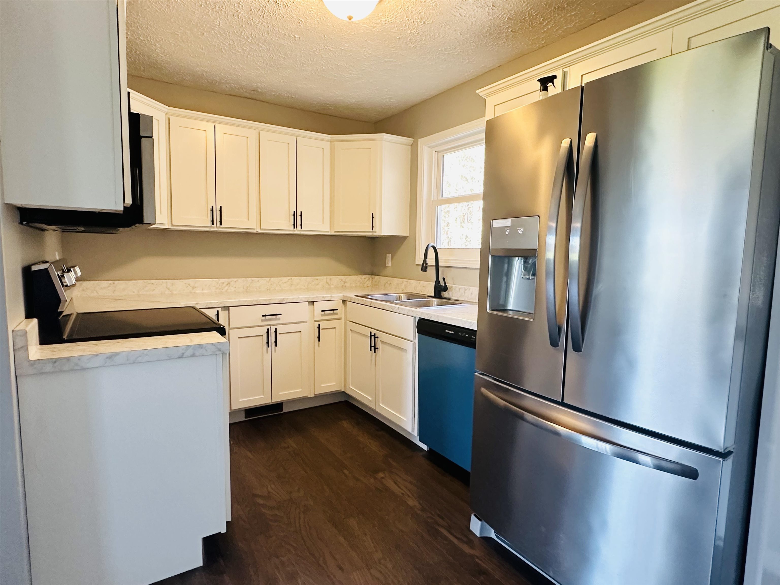 623 Bethesda-Purdy Road Selmer, TN 38375 - Photo 7 of 19 Kitchen with appliances with stainless steel finishes, dark hardwood / wood-style flooring, a textured ceiling, sink, and white cabinets