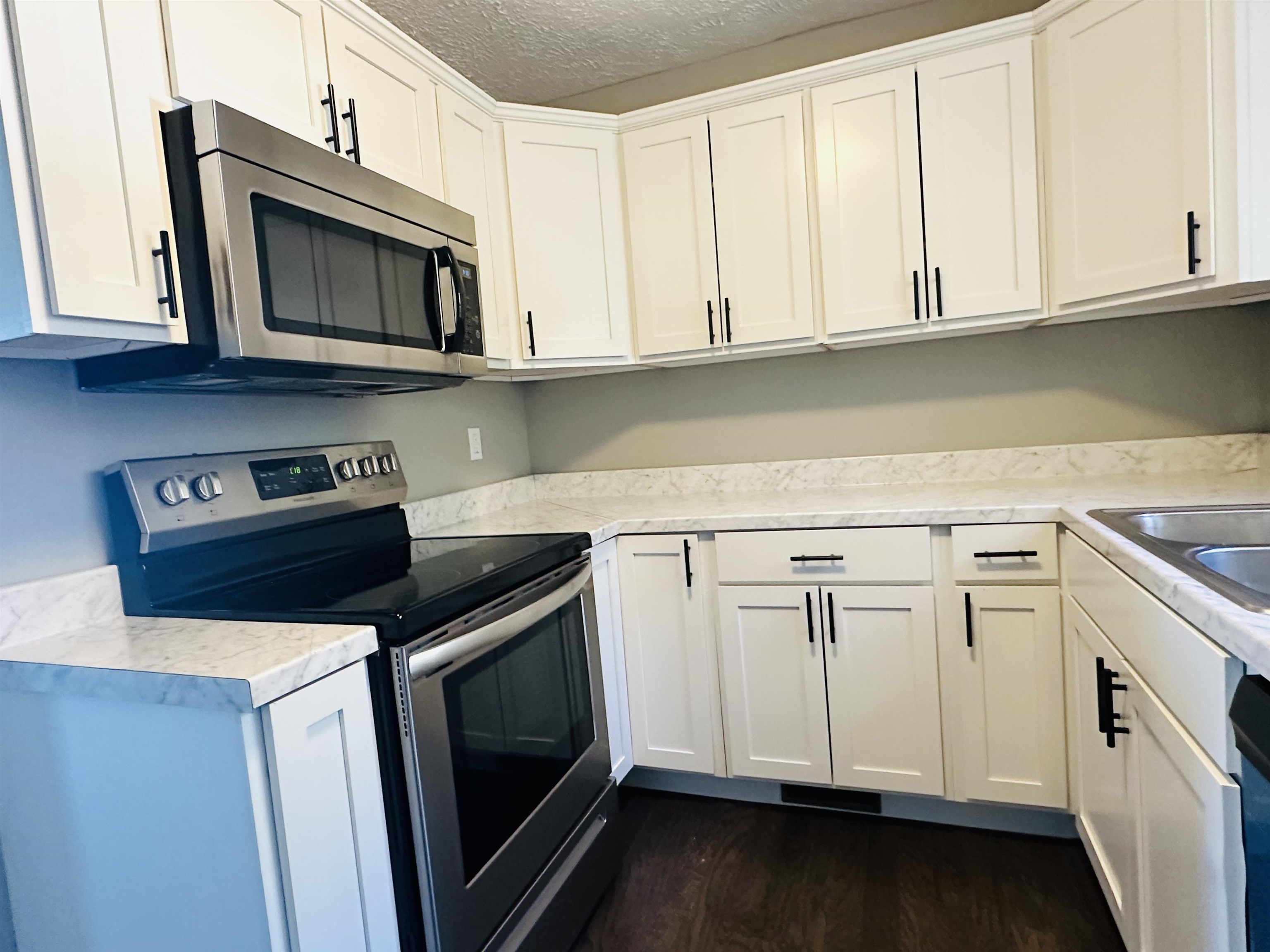 623 Bethesda-Purdy Road Selmer, TN 38375 - Photo 9 of 19 Kitchen with sink, dark hardwood / wood-style floors, a textured ceiling, white cabinets, and appliances with stainless steel finishes