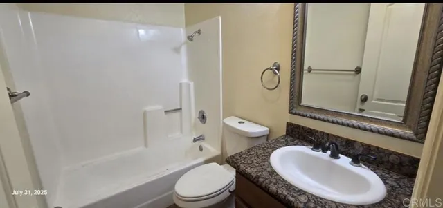 a bathroom with a granite countertop toilet a sink and a mirror