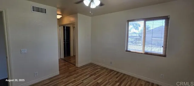 an empty room with wooden floor cabinet and windows