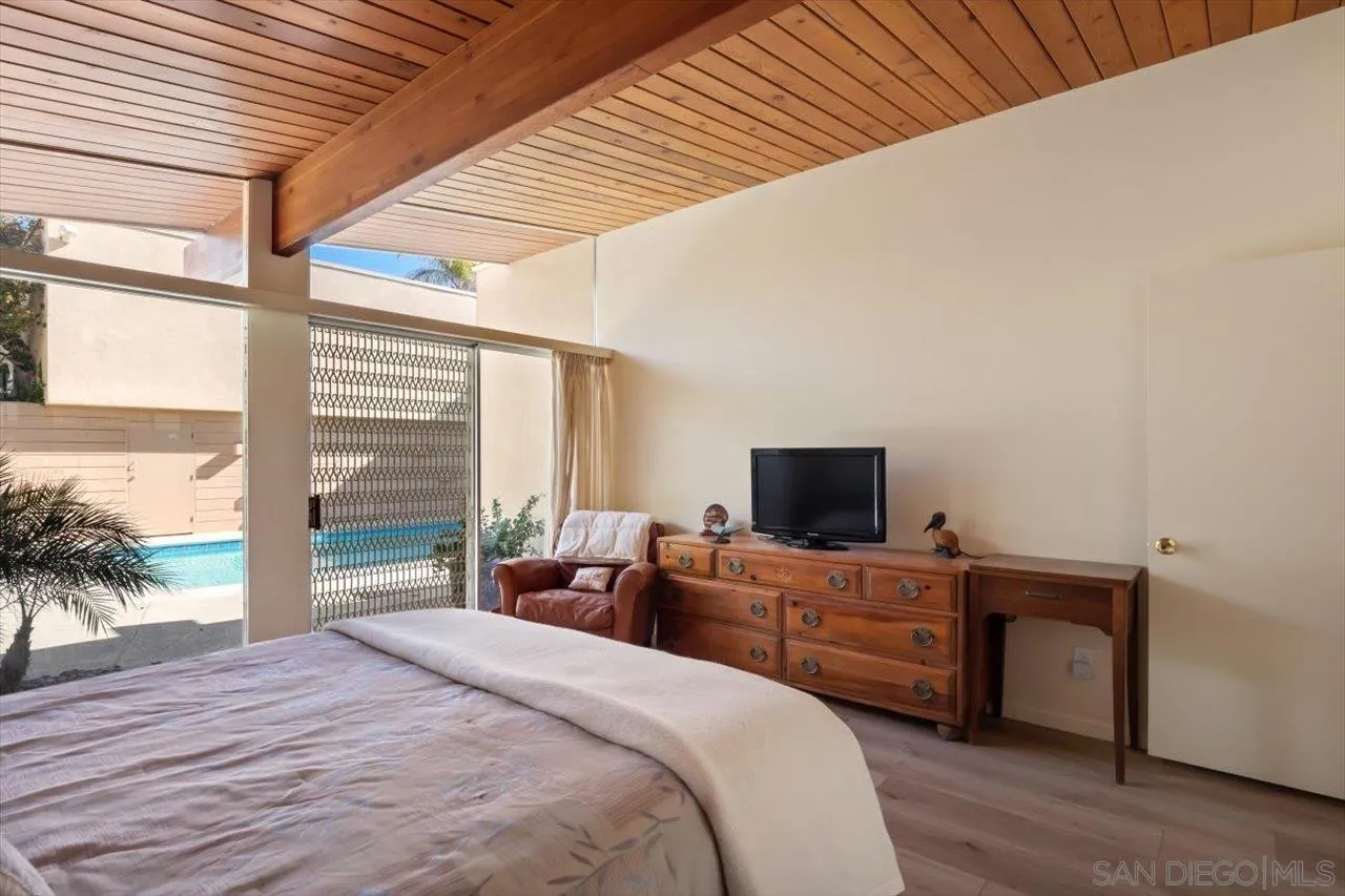 2681 Ocean Street Carlsbad, CA 92008 - Photo 13 of 36 a bedroom with a bed and a flat tv screen next to a large window