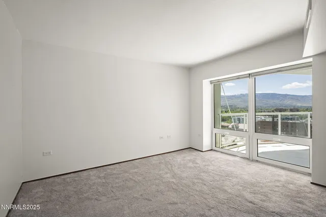 an empty room with floor to ceiling window and an outdoor view
