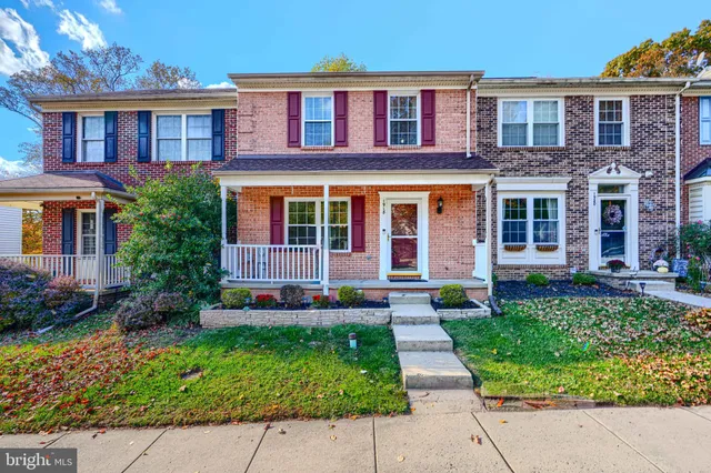 front view of a brick house with a yard and plants