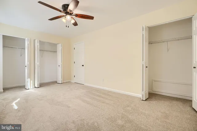 an empty room with closet and a ceiling fan