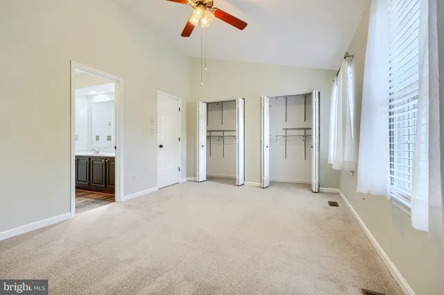 an empty room with chandelier fan and windows