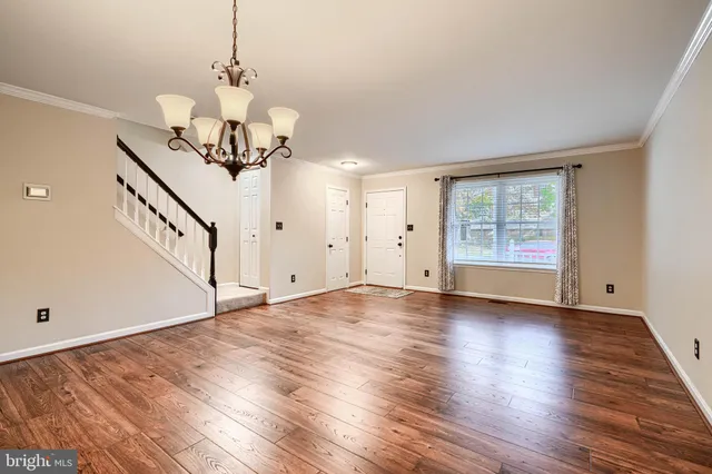 a view of a room with wooden floor chandelier and windows