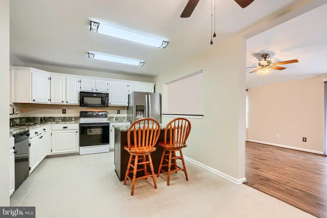 a kitchen with stainless steel appliances kitchen island granite countertop a table chairs microwave and sink